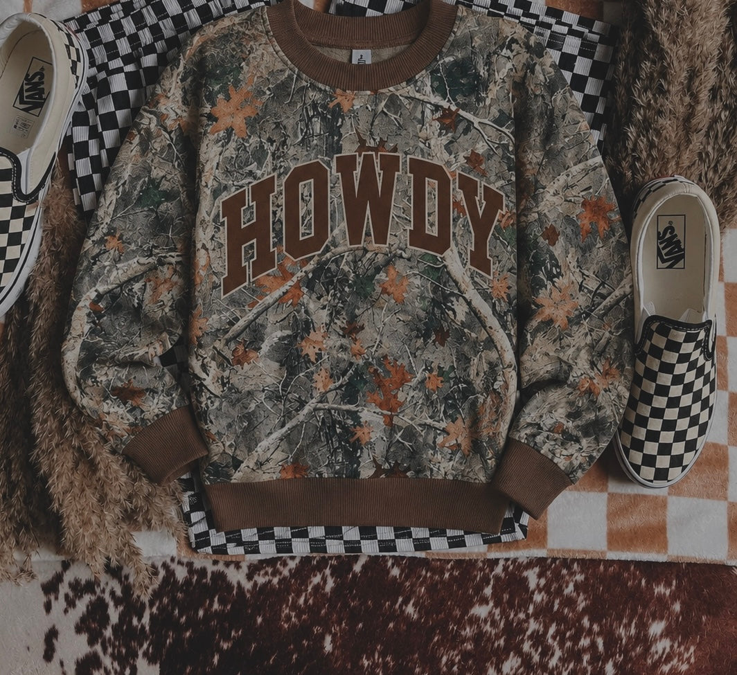 A folded pink T-shirt on a leopard print fabric, with Just Pray printed in bold letters featuring checkered, leopard, and polka dot patterns. A disco ball is in the top right corner.