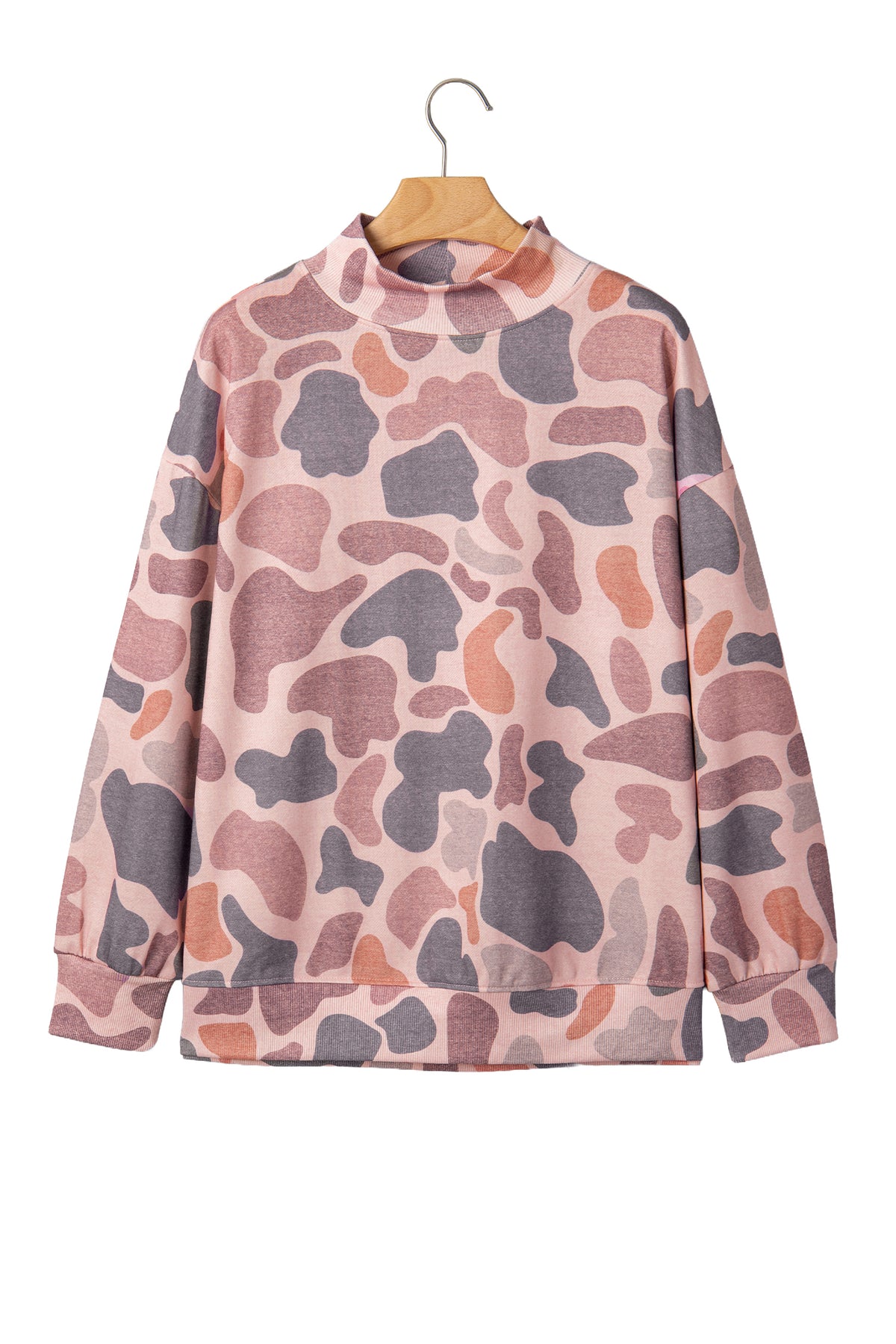 The Camo Mock Neck Pullover Sweatshirt features long sleeves, a high mock neckline, and a relaxed tunic silhouette in a pink, purple, and brown camouflage print. It is displayed on a wooden hanger against a white background.