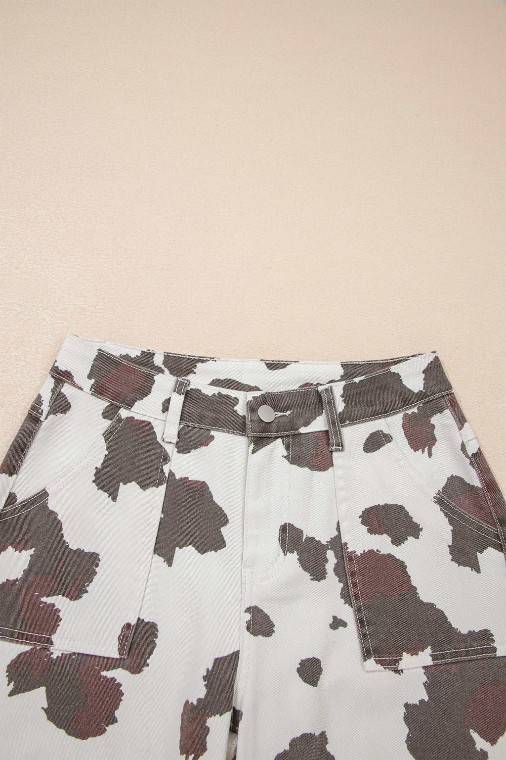 Multi-pocket jeans in white fabric with Brown Cow Print pattern and visible large brown patches on a cotton blend material.