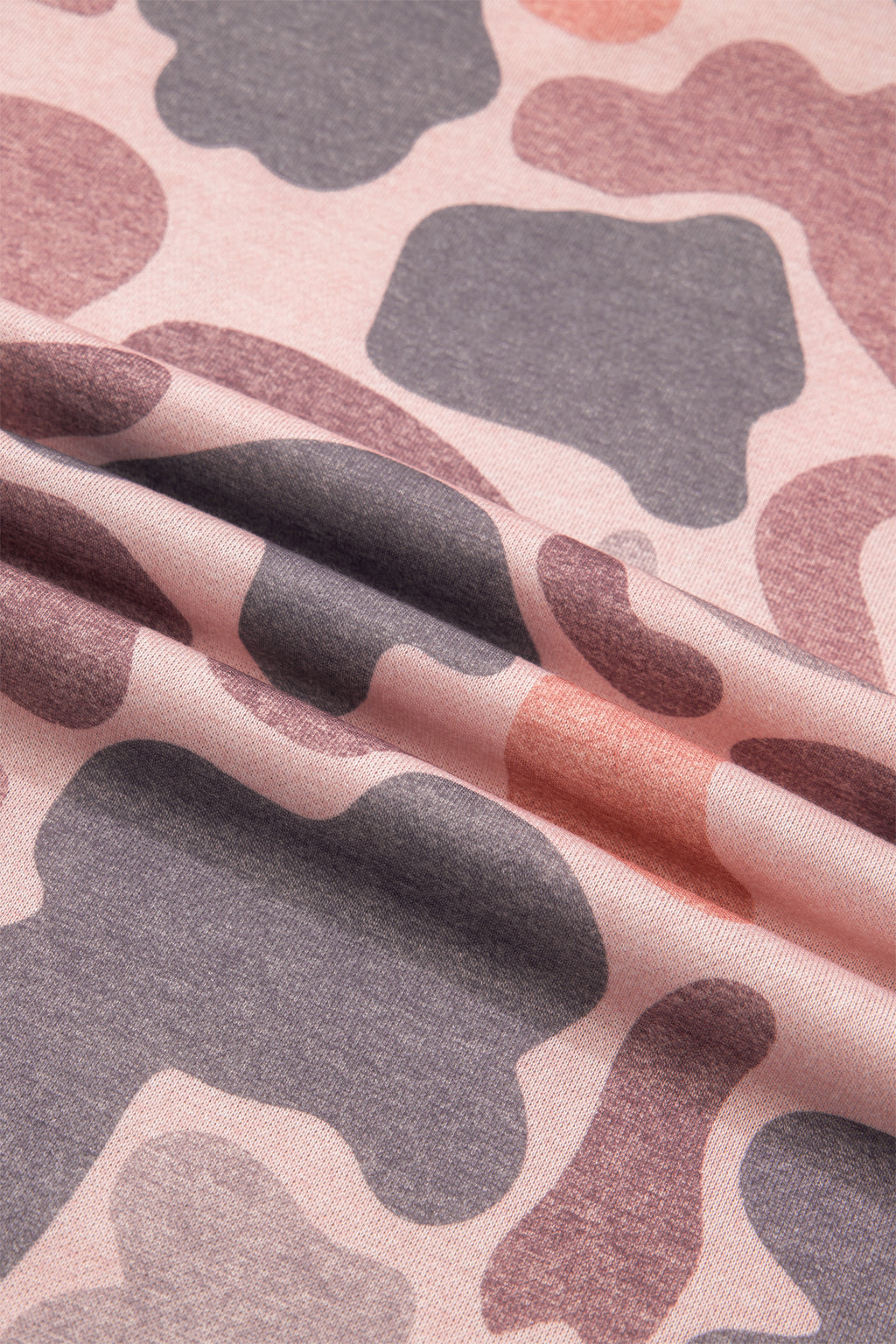 Pink fabric with an abstract camo pattern in shades of purple, gray, and muted red is displayed with gentle folds and a soft texture—ideal for creating the Camo Mock Neck Pullover Sweatshirt.