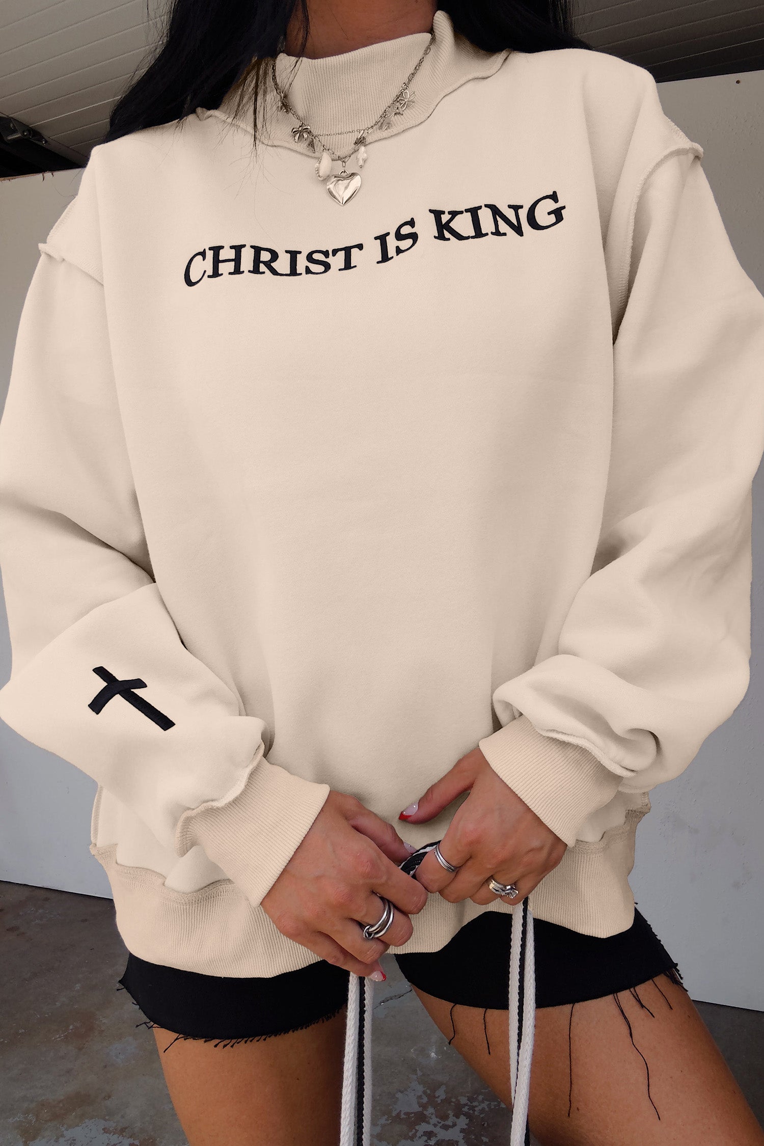 Original model detail view of the Beige CHRIST IS KING Embroidery High Neck Baggy Sweatshirt