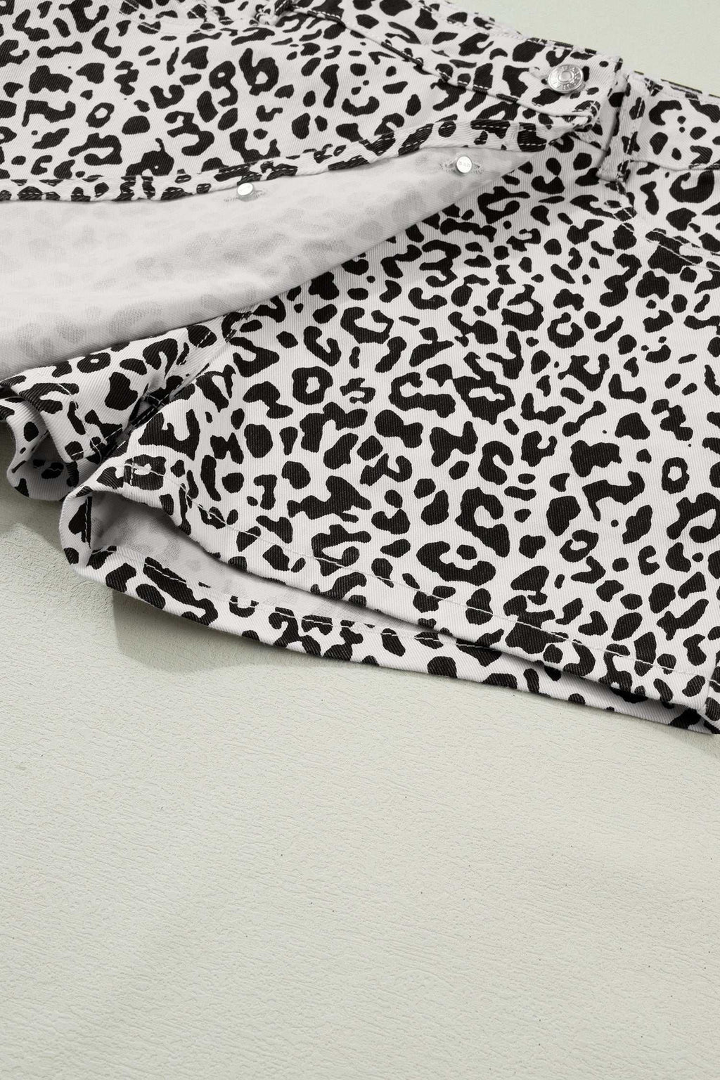 Black Leopard Button Overlap Denim Shorts in white with black leopard print and a button overlap front design