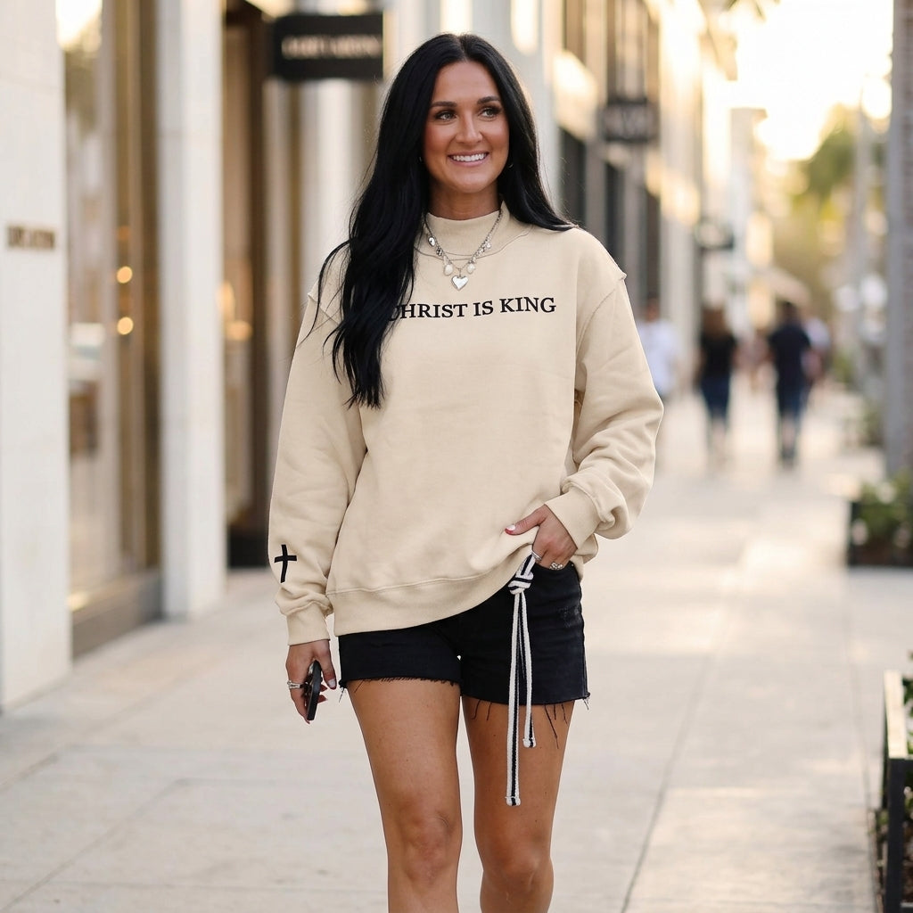 Street style model wearing the Beige CHRIST IS KING Baggy Sweatshirt with denim during golden hour